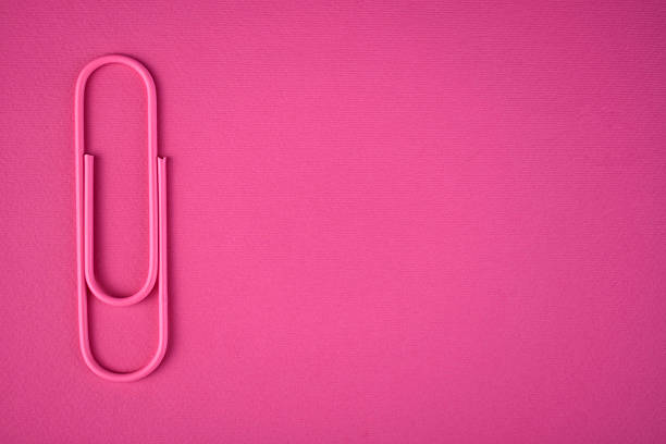 Pink stationery paper clip on a pink background. Copy space.