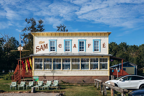 Baie-Sainte-Catherine, Canada - August 21, 2025: Historic Chez Sam hotel and restaurant building with vintage facade and Quebec flag