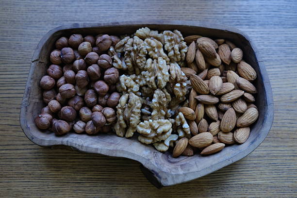 Mix of nuts in a wooden plate; almonds, hazelnuts and walnuts
