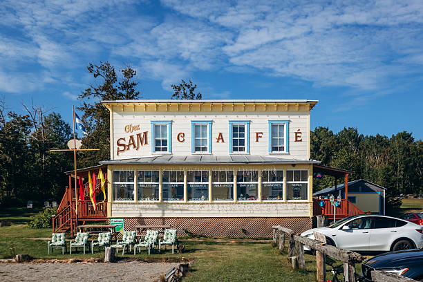 Baie-Sainte-Catherine, Canada - August 21, 2025: Historic Chez Sam hotel and restaurant building with vintage facade and Quebec flag