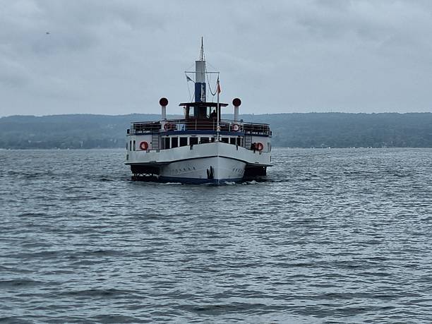 A boat is sailing on a calm lake at sunset. The sky is filled with clouds, and the water is still. The boat is the only thing visible in the scene, and it is moving slowly