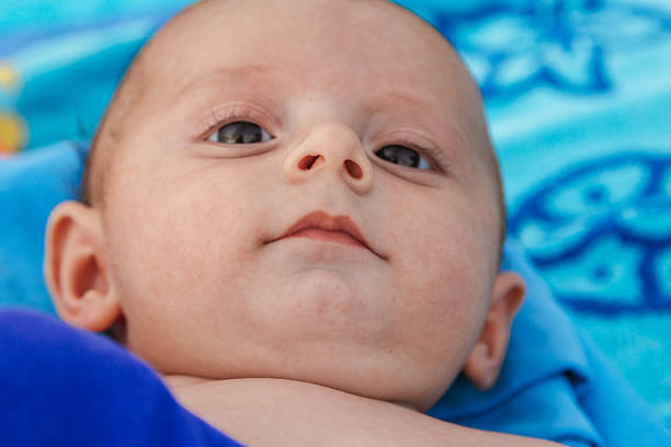 Baby lying on a soft blue blanket, gentle eyes open in a serene close-up portrait capturing innocence, comfort and new life