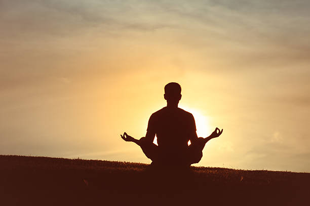 istock Silhouette of Man Meditating in Lotus Pose at Sunset 2261998549