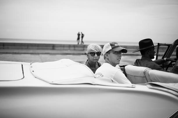 Havana, Cuba - October 9, 2018: People riding in a vintage convertible car near the Malecon seaside promenade.