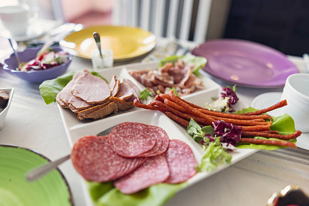 Platter of cold cuts is placed at the center of the festive Easter table setting. Fresh greens, colorful plates fill the table, creating a bright, celebratory atmosphere for the holiday meal.Shot with Canon R5