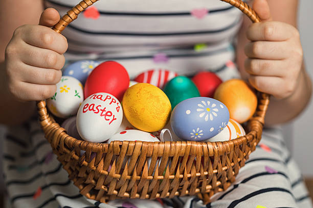 Little girl holding the basket with painted eggs. Happy Easter