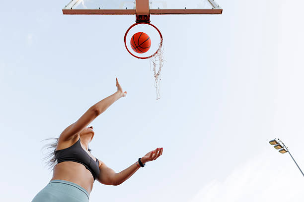 Active Asian amateur basketball player is practicing or playing basketball at the outdoor street basketball course. Asian young man is doing an outdoor exercise alone. Healthy lifestyles concept.