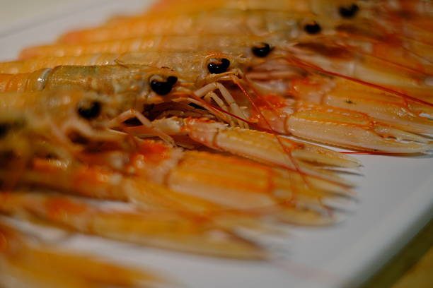 This dish features some grilled crawfish, presented on a white porcelain plate. The crawfish maintain their distinct segmented shell structure, exuding a tantalizing aroma. Alongside, a small ramekin of lemon butter sauce is provided, offering a complementary sweet and tangy flavor profile to the succulent crawfish meat.