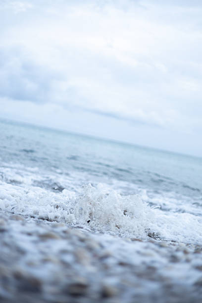 Calm ocean waves crashing on a sandy beach under cloudy sky during daytime