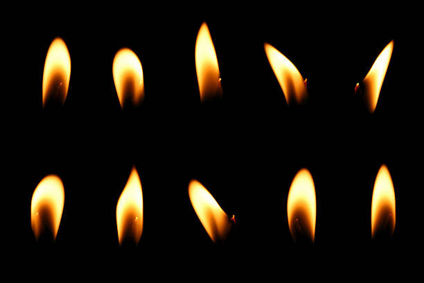 candle with a glowing orange and gold flame, isolated on a black background. light effect candle fire flame