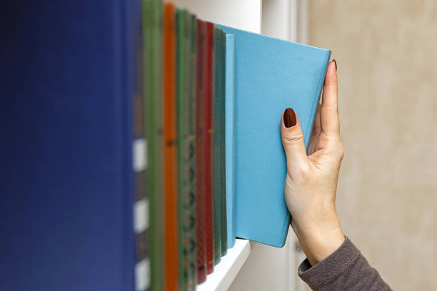 A group of books leaning against a wall at the foot of a window