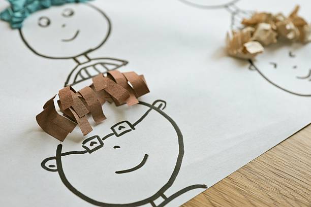 Close-up of a child's drawing with simple faces and creative paper hair textures, showcasing a fun art activity