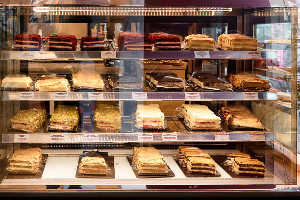 Display case filled with various layered cakes and pastries in a bakery, showcasing diverse flavors and textures in an inviting setting