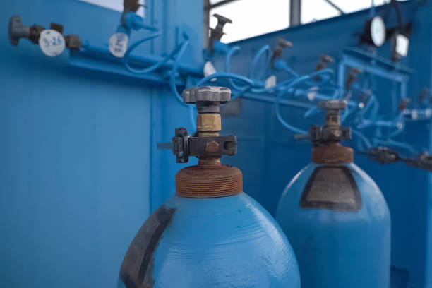 The image shows a pressurized oxygen cylinder with a mounted pressure regulator that has two pressure gauges. The gauges are used to measure the gas pressure — one shows the oxygen pressure inside the cylinder, while the other shows the working oxygen pressure coming out of the regulator.This type of equipment is commonly used in welding, medicine, and industry where precise oxygen dosing is important. The background of the image is blurry and indistinct, which further highlights the technical details in the foreground.