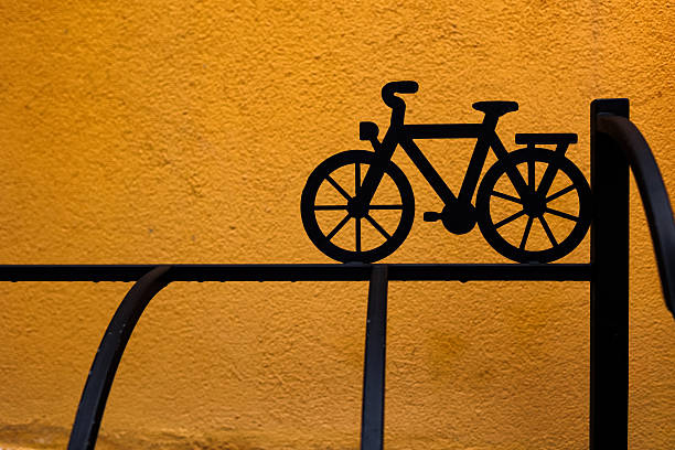Black metal bicycle silhouette on bright yellow background. Minimalist design, creative artwork, and artistic composition concept.