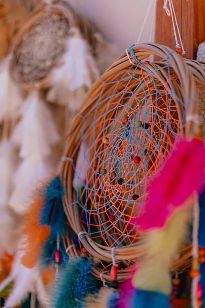 A colorful dream catcher with feathers and beads hanging from it. The feathers are in various colors and sizes, and the beads are scattered throughout the web. The dream catcher is a beautiful