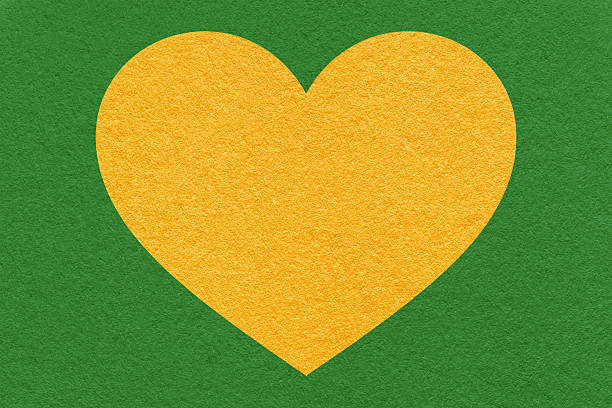 Yellow heart shape on green textured paper background with copy space, eco friendly abstract symbol for banner.