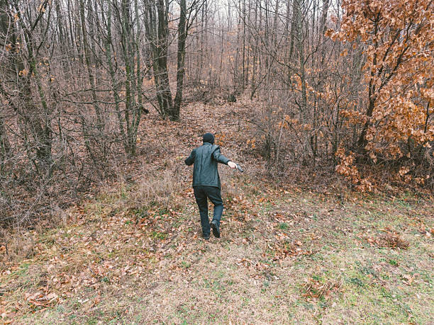 Criminal with hand gun running away in the forest
