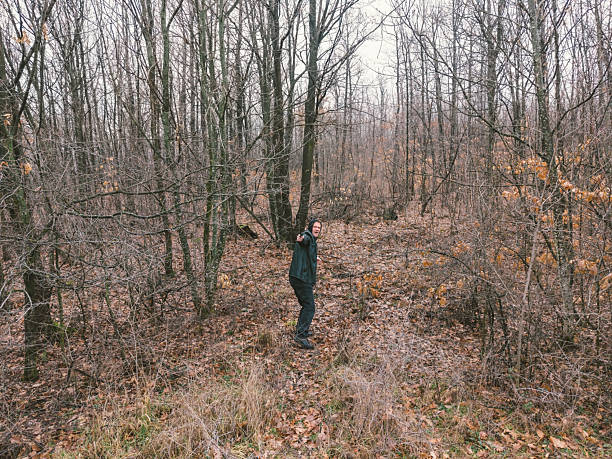 Criminal running in the forest and aiming with hand gun