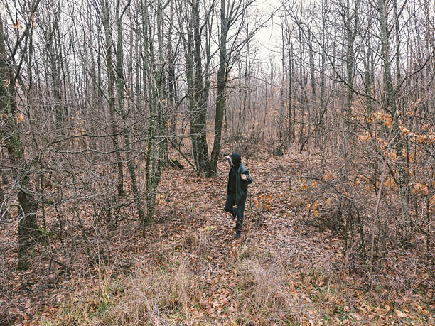 Criminal running in the forest and aiming with hand gun