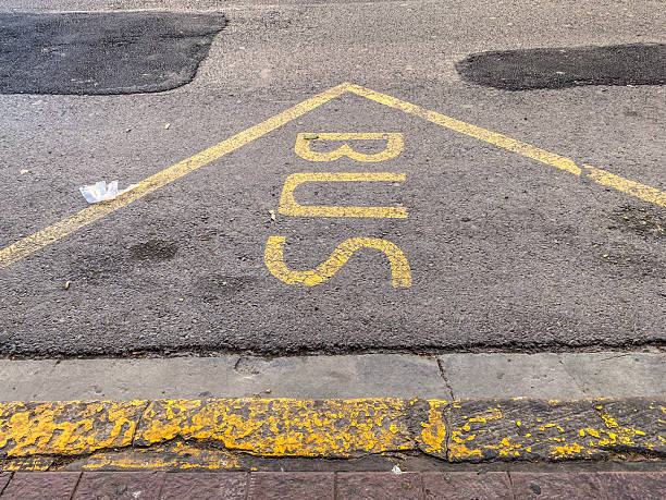 White painted letters indicate a designated bus stop on a city street, showcasing the urban infrastructure and public transport system.