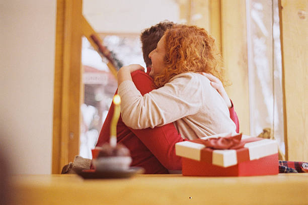Young couple holding and showing wrapped gift at home