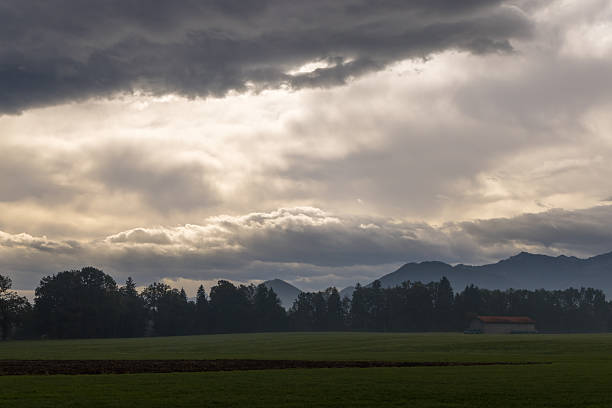 dunkle und helle  Gewitterwolken über Wiesen  Wald Bergen