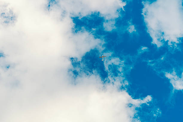 Small airplane cruising high in a vast blue sky dotted with white clouds, evoking travel, freedom and serene adventure as it journeys toward distant horizons and new destinations