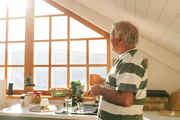 Senior Man Enjoying Morning Coffee By The Window In Bright Kitchen
