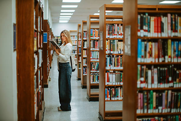 Female student browsing a library, reading books and looking for study materials. Real student lifestyle moment showing everyday education and academic routine in New York.