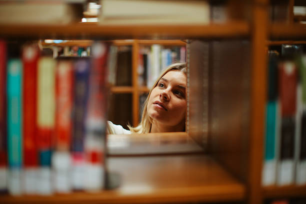 A person reaching for a book on a library shelf, showcasing dedication to learning and exploration in a tranquil academic setting.