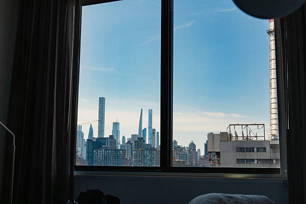 Urban skyline framed by a room window with curtains, combining interior space and distant skyscrapers to show modern city living perspective