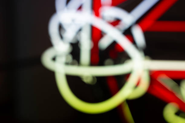 In the city at night, blurred neon light and fluorescent blur form an abstract background, trails of movement like glowing tubes, their velocity drawing bright lines across the journey