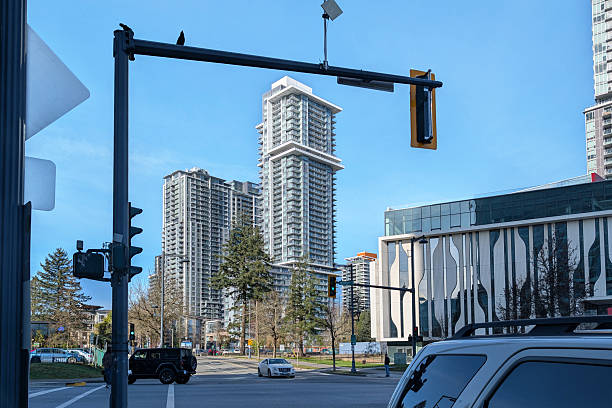 Surrey, Canada - February 11, 2026: Looking northwest from 102nd Avenue at University Drive. Modern condominium complexes stand along Central Avenue. Part of the Simon Fraser University Surrey Engineering Building (SRYE) is to the right. Two birds perch on a traffic light crossarm. Winter morning with a clear sky over Metro Vancouver.