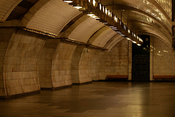 An empty underground metro station platform features a grand arched ceiling with rows of lights and walls clad in polished marble, creating a sense of spaciousness and quiet