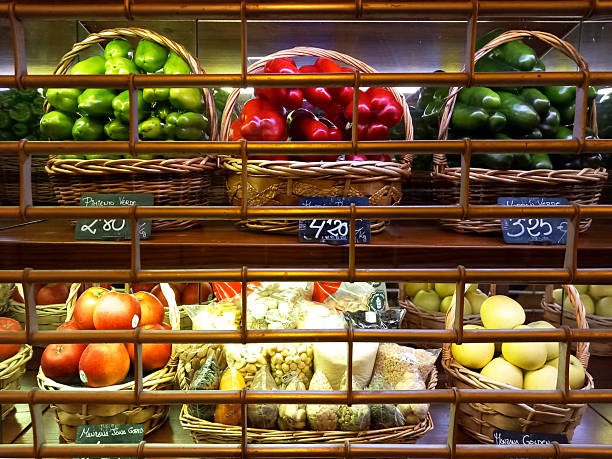 Colorful vegetables in groceries store, red and green peppers, cucumbers, apples in baskets.