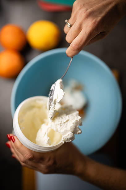 Hands adding ricotta cheese to bowl for baking recipe