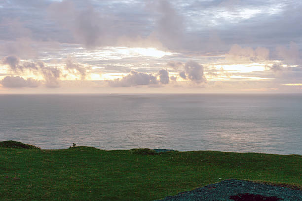 A beautiful view of the ocean with a cloudy sky. The sky is a mix of blue and orange, creating a serene and peaceful atmosphere. The ocean is calm