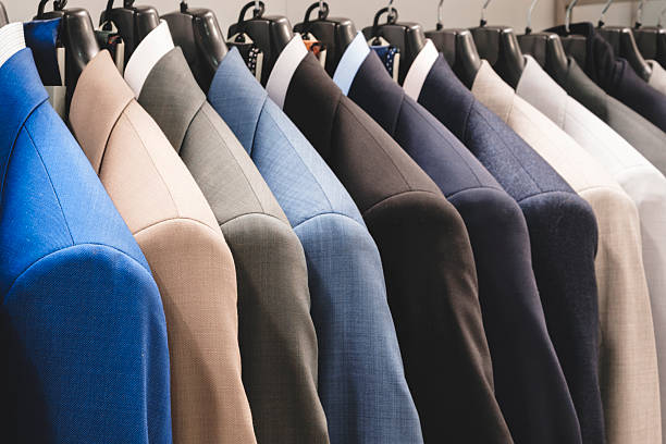 istock Row of men's suits hanging. Elegant jacket hanged on a clothes rack. 2262175396