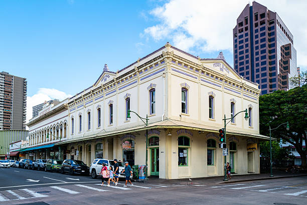 Honolulu, HI, U.S.A. - Nov. 9, 2025: Pedestrians cross the street in front of the historic Perry Block building at the intersection of Nuʻuanu Avenue and Hotel Street. Built in 1888, this landmark is a contributing structure of the Honolulu Chinatown Historic District.