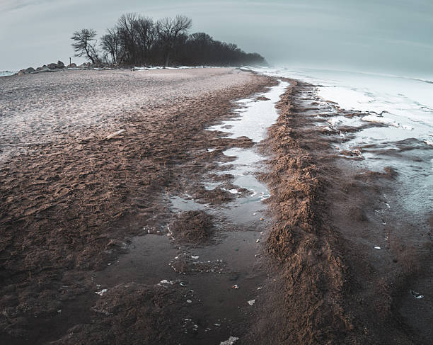 Ice is forming along the shore of a frozen lake with a beautiful cloudy sky in the background