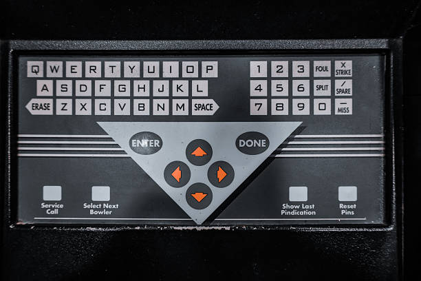 Retro bowling alley scoring keypad and control panel featuring QWERTY and numeric buttons, directional pad and function keys for entering player names, scores and lane options on a console.