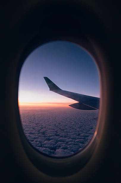 istock Airplane Wing Seen Through Window at Sunrise Above the Clouds 2262213599