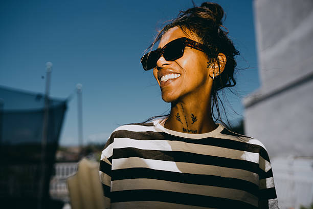 Young woman smiling outdoors in sunny setting.