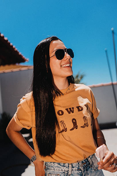 Young woman with sunglasses standing outdoors in bright sunlight.