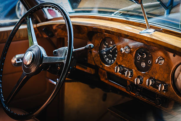 Detailed view of a retro car interior featuring analog instrument gauges, textured wooden dashboard, leather upholstery, and chrome trim for authentic vintage automotive content.