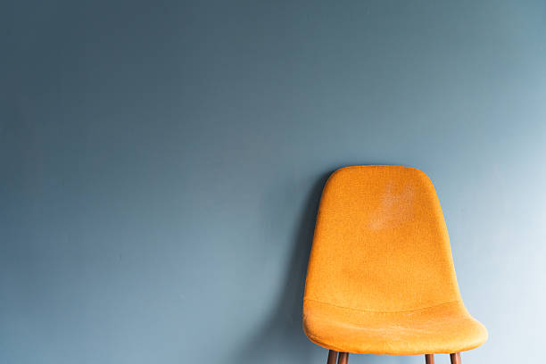 Minimalist interior featuring a bright yellow chair positioned in front of a blue wall. Clean design, bold color contrast, modern aesthetic, and simple contemporary composition with empty space for text or design.