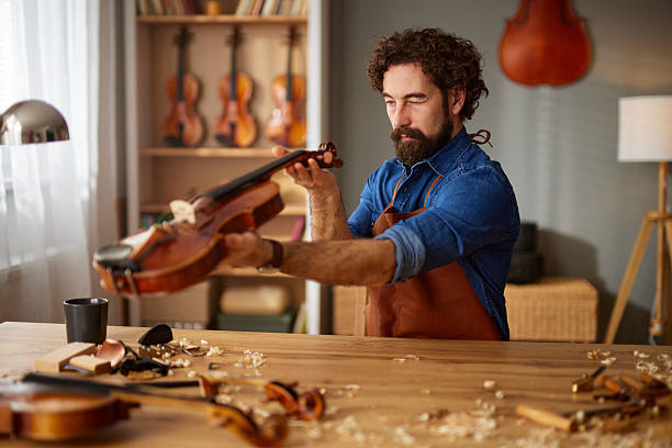 Male artisan examining a string instrument, showing craftsmanship and expertise