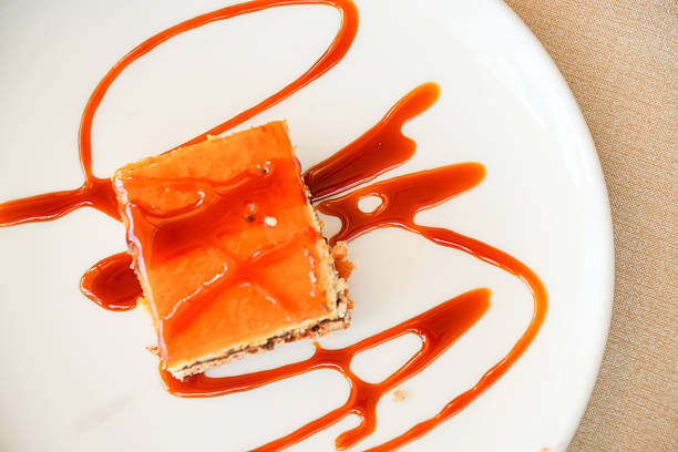 A dessert with a caramel drizzle on top of a white plate. The plate is placed on a table