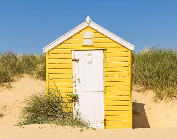 Yellow wooden beach hut on the sandy beach in Southwold, Suffolk. UK